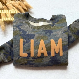 May include: A camouflage sweatshirt with the name "LIAM" in orange letters.