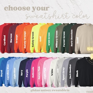 Puede incluir: Una selecci&oacute;n de 20 sudaderas unisex Gildan en varios colores, incluyendo rojo, cardenal, granate, naranja, naranja de seguridad, verde de seguridad, dorado, verde irland&eacute;s, verde militar, verde bosque, chocolate negro, arena, zafiro, azul real, azul Carolina, azul claro, azul marino, morado, heliconia, rosa de seguridad, rosa claro, blanco, ceniza, gris deportivo, gris oscuro y negro. El texto "choose your sweatshirt color" est&aacute; en la parte superior de la imagen. El texto "gildan unisex sweatshirts" est&aacute; en la parte inferior de la imagen.