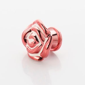 Puede incluir: Un pomo de armario en forma de rosa de color rosa y blanco.