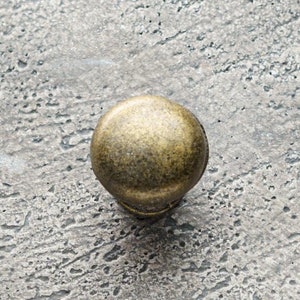 以下が含まれることがあります： 表面がテクスチャ加工された丸い金色調のキャビネットノブ