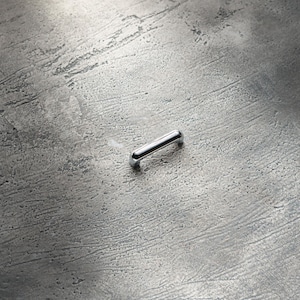 May include: A silver metal cabinet handle with rounded edges.