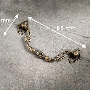 Könnte beinhalten: Antiker Schubladengriff aus Bronze mit aufwendigen Details. Der Griff ist 3,7 cm breit und 8,5 cm lang. Verfügt über ein dekoratives Sternmuster in der Mitte. Ideal für die Restaurierung antiker Möbel.