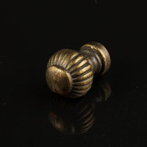 May include: A small, round, antique brass cabinet knob with a fluted design.