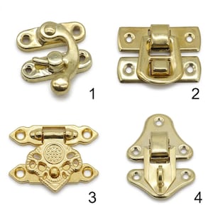 May include: Four distinct gold-toned metal box latches labeled 1 through 4. Latch 1 is a swivel hook, 2 is a rectangular flip-top, 3 features an ornate decorative plate with a central circular pattern, and 4 is a triangular-shaped toggle latch.