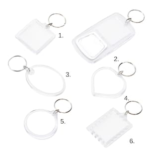 Könnte beinhalten: Eine Sammlung von sechs transparenten Acryl-Schlüsselanhängern in verschiedenen Formen: quadratisch, rechteckig, oval, herzförmig und rund. Jeder Schlüsselanhänger hat einen silbernen Metallring zum Befestigen von Schlüsseln. Die Schlüsselanhänger sind leer und bereit zur individuellen Gestaltung.