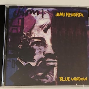 Könnte beinhalten: Ein CD-Gehäuse mit einem farbenfrohen abstrakten Gemälde eines Gesichts. Der Text "Jimi Hendrix" und "Blue Window" ist in Gelb auf dem Gehäuse aufgedruckt.