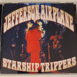 May include: A CD case with a colorful image of the band Jefferson Airplane. The band's name is in large, white, psychedelic letters. The text "Starship Trippers" is in white letters with a yellow outline. The image shows the band performing on stage.