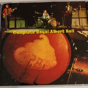 May include: A CD case with a black spine and a clear front cover. The front cover features a photo of a band performing on stage. The text "Complete Royal Albert Hall" is printed in yellow on a red background.