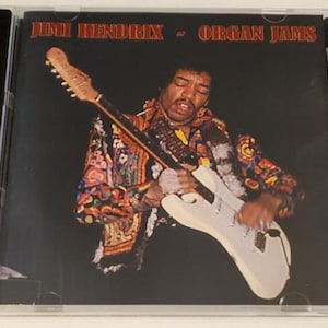 May include: A CD cover featuring Jimi Hendrix playing a white electric guitar. The album cover is titled "Jimi Hendrix - Organ Jams".