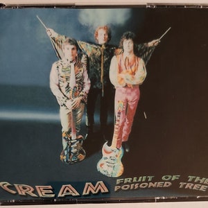 May include: CD case featuring the band Cream. The cover art shows three men in colorful outfits, each holding a guitar. The band's name, "Cream," is at the bottom left, with "Fruit of the Poisoned Tree" on the right.