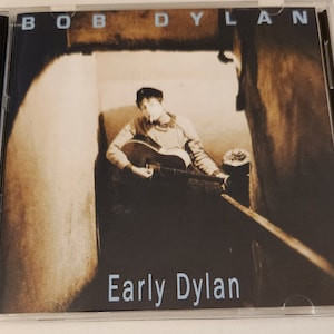 May include: A CD case with a sepia-toned photo of Bob Dylan sitting on a staircase, holding a guitar. The text "BOB DYLAN" is at the top of the case and "Early Dylan" is at the bottom.