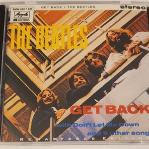 Puede incluir: Una portada de álbum de vinilo vintage con The Beatles. El álbum se titula "Get Back" con el texto "with Don't Let Me Down and 9 other songs" debajo. La portada presenta una foto de los miembros de la banda de pie en una escalera.