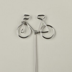 May include: A silver wire sculpture of a bicycle with a long, thin stem.