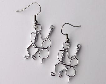 May include: A pair of silver-colored wire earrings. Each earring features a stylized musician playing a cello. The musician and cello are crafted from a single piece of wire, with a hook for the ear.