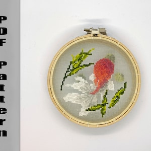 May include: A cross-stitch embroidery hoop featuring a design of a red and white flower with green accents. The embroidery is set against a sheer fabric within a natural wood hoop. The text "PDF Pattern" is printed vertically on the left side.