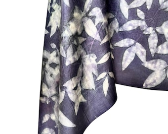 May include: A dark purple fabric scarf featuring a botanical print of white leaves. The textile displays a natural, organic pattern with varying shades of deep violet and crisp white, creating a high-contrast design across the entire surface.