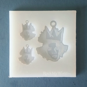 Puede incluir: Un molde de silicona transparente con tres dise&ntilde;os de caras coronadas de diferentes tama&ntilde;os. El dise&ntilde;o m&aacute;s grande est&aacute; en el centro. El texto "Rock My World Inc" es visible en la parte inferior.