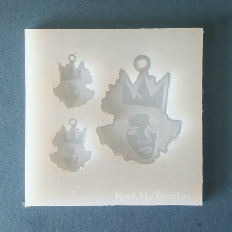 Puede incluir: Un molde de silicona transparente con tres dise&ntilde;os de caras coronadas de diferentes tama&ntilde;os. El dise&ntilde;o m&aacute;s grande est&aacute; en el centro. El texto "Rock My World Inc" es visible en la parte inferior.