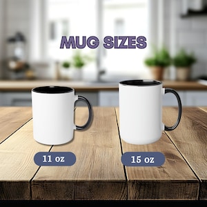 May include: Two white ceramic mugs with black interiors and handles. The left mug is labeled 11 oz and the right mug is labeled 15 oz. The text MUG SIZES appears above the mugs. The mugs are displayed on a wooden surface.
