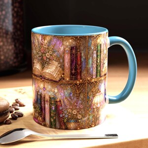 May include: A ceramic mug with a light blue interior and handle, featuring a wrap-around print of a detailed library scene. The design displays shelves filled with colorful books, open volumes, floral arrangements, and a lamp, all rendered in a shimmering, textured, and ornate artistic style.