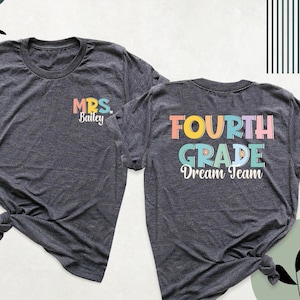 May include: Two grey t-shirts with a rainbow colored design. The front shirt says "MRS. Bailey" and the back shirt says "FOURTH GRADE Dream Team".