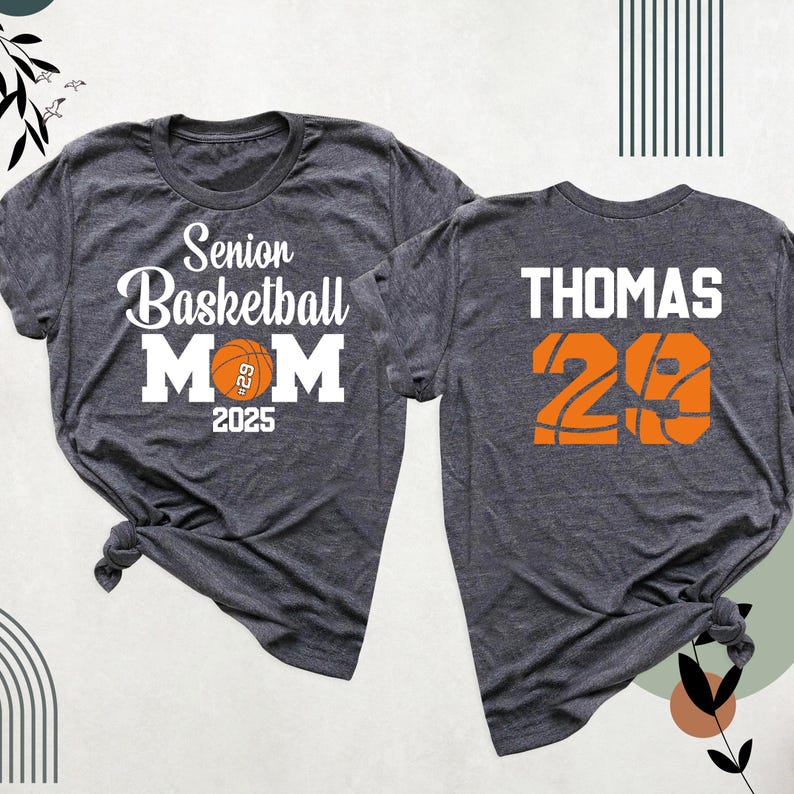 May include: Two grey t-shirts. One shirt says "Senior Basketball Mom 2025" with a basketball graphic. The other shirt says "THOMAS 29" with a basketball graphic.