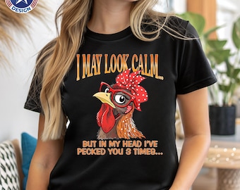 May include: A black short-sleeved t-shirt featuring a graphic of a chicken wearing red glasses and a red polka-dot headscarf. The text reads: I MAY LOOK CALM... BUT IN MY HEAD I'VE PECKED YOU 3 TIMES...