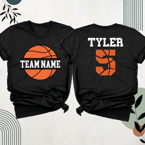 May include: Two black t-shirts with a basketball design. One shirt has the text "TEAM NAME" and a basketball graphic. The other shirt has the text "TYLER" and the number "5" with a basketball graphic.