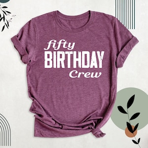 May include: A purple t-shirt with the text "fifty birthday crew" in white.