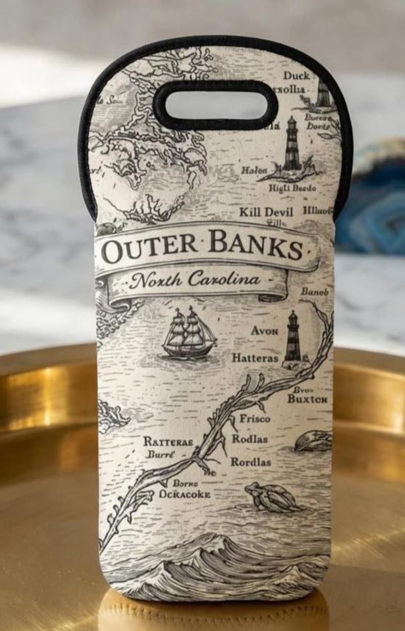 May include: A neoprene wine bottle carrier featuring a map of the Outer Banks, North Carolina. The black and white design includes nautical elements, place names, and the text "Outer Banks". It has a black handle.