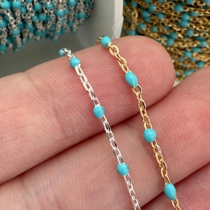 May include: Two strands of chain with turquoise beads. One strand is silver and the other is gold.