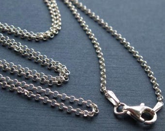 May include: A silver chain necklace with a lobster clasp closure. The chain is made of small, round links.