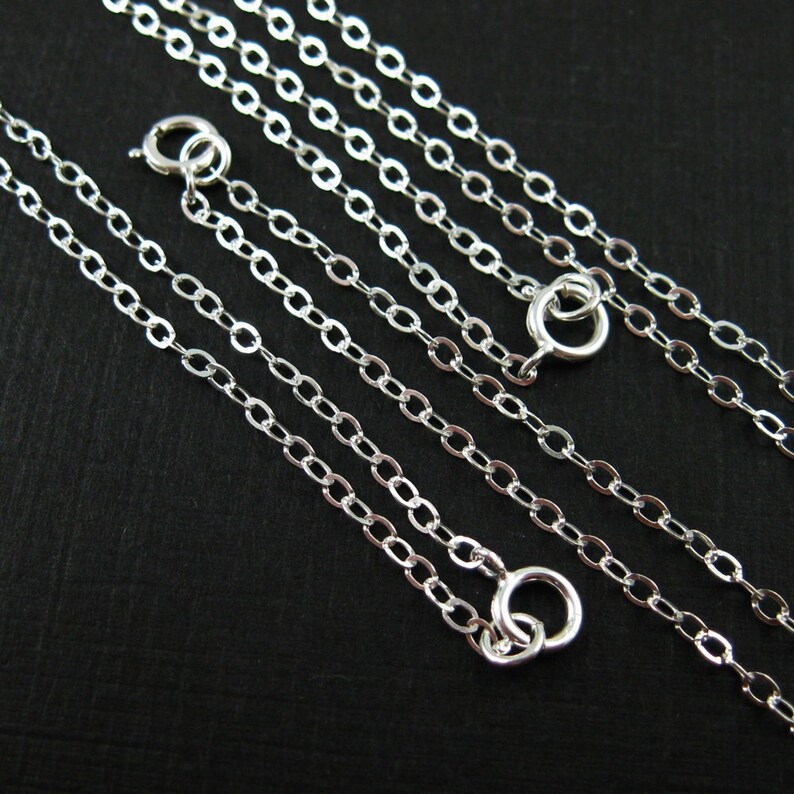 May include: Four silver chain necklaces of varying lengths, each with a lobster clasp closure.