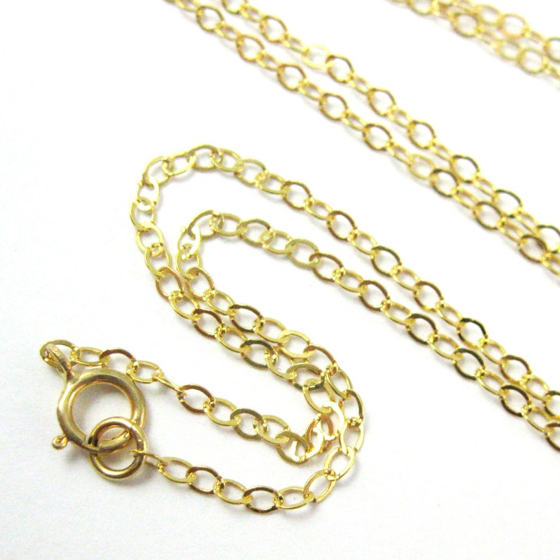 May include: A gold chain necklace with a lobster clasp closure. The chain is made of oval links.