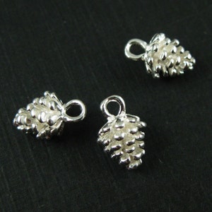 May include: Three silver pine cone charms with a loop for attaching to jewelry or other crafts.