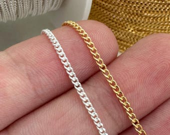 Könnte beinhalten: Zwei Kettenstränge, einer silber und einer gold, werden in einer Hand gehalten. Die Ketten sind beide Gliederketten mit einem klassischen Design.