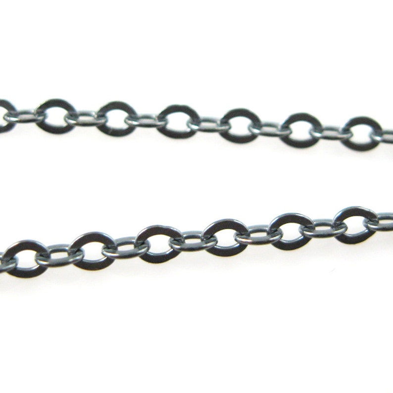 May include: A close-up of a silver chain with oval links. The chain is lying flat on a white surface.