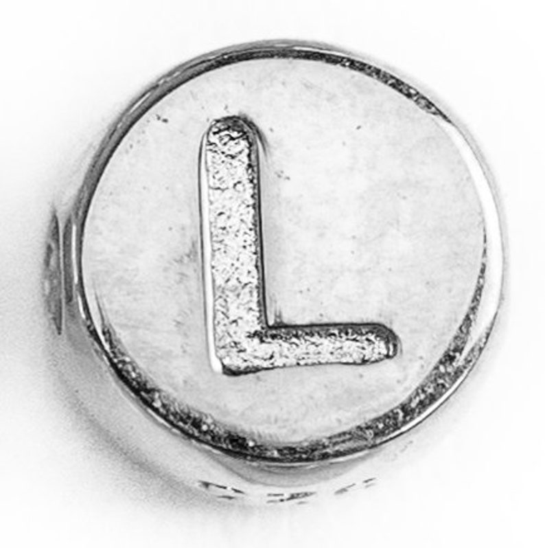 May include: Silver charm bead with the letter L embossed on the front.