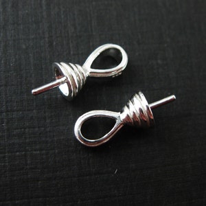 May include: Two silver-toned metal bead tips with a loop at the top and a pin at the bottom. The bead tips are designed to be used for making jewelry.