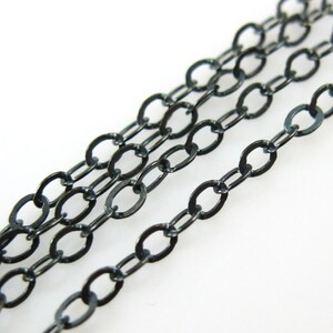 May include: A close-up of a black chain with oval links. The chain is made of metal and has a smooth, polished finish.
