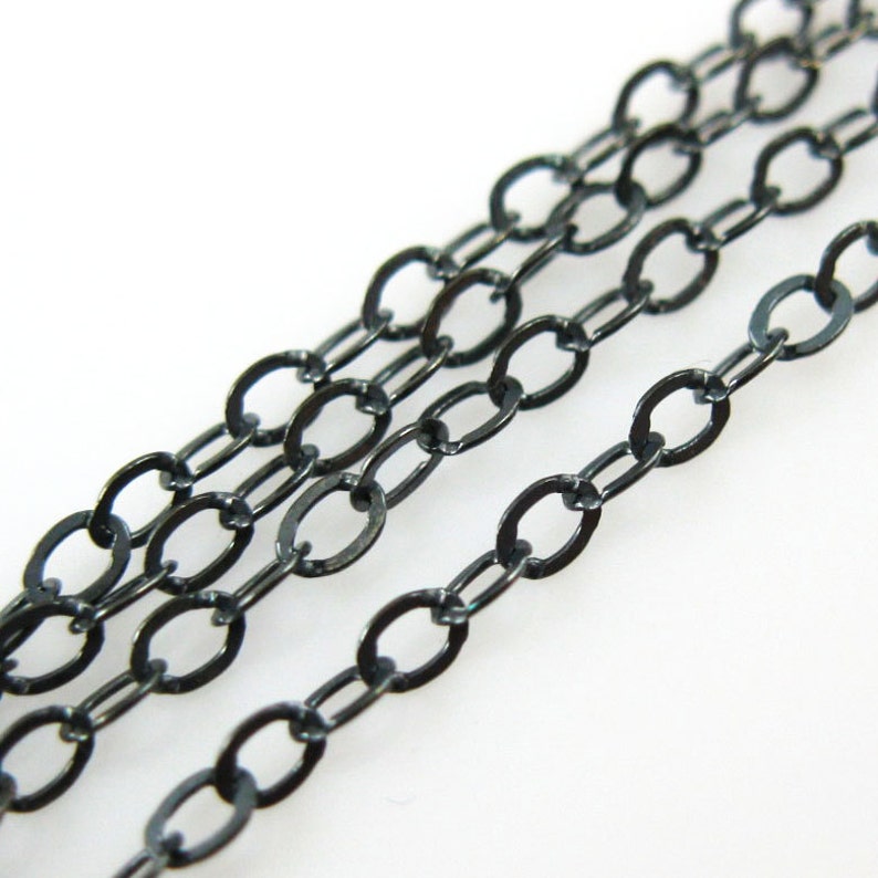 May include: A close-up of a black chain with oval links. The chain is made of metal and has a smooth, polished finish.