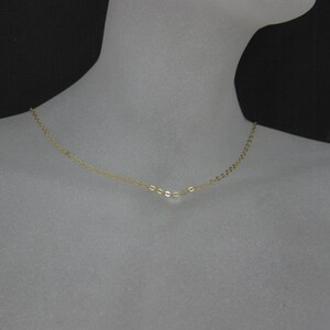 May include: A delicate gold chain necklace with a simple, oval-shaped link design.