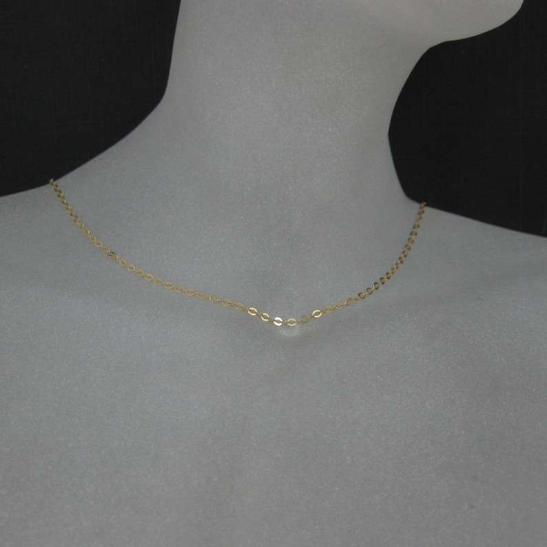 May include: A delicate gold chain necklace with a simple, oval-shaped link design.