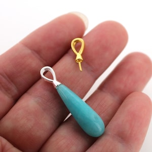 Puede incluir: Dos anillas para colgantes, una dorada y otra plateada, con un colgante de lágrima turquesa.