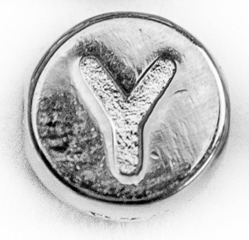May include: A silver charm featuring the letter Y embossed on it.