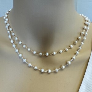 Puede incluir: Dos collares superpuestos con perlas blancas. Las perlas est&aacute;n ensartadas en una fina cadena dorada, creando un dise&ntilde;o cl&aacute;sico y elegante. Los collares se exhiben en un maniqu&iacute;, mostrando la delicada naturaleza de la joyer&iacute;a. Las perlas son de diferentes tama&ntilde;os.