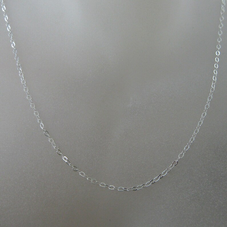 May include: A silver chain necklace with a delicate, oval-shaped link design.