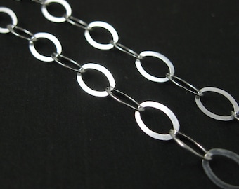 May include: A silver chain necklace with oval links. The chain is on a black background.