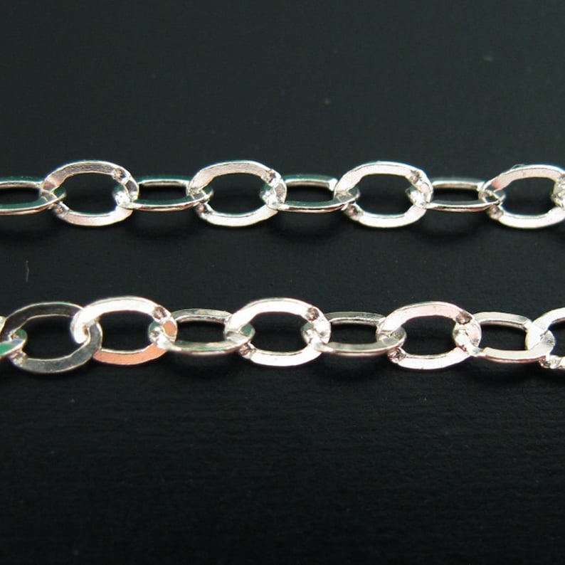 May include: A silver chain with oval links. The chain is made of metal and has a shiny finish.