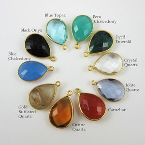 May include: Assortment of 10 teardrop-shaped gemstone pendants with gold-plated bail settings. Gemstones include blue topaz, peru chalcedony, dyed emerald, crystal quartz, iolite quartz, carnelian, citrine quartz, gold rutilated quartz, black onyx, and blue chalcedony.